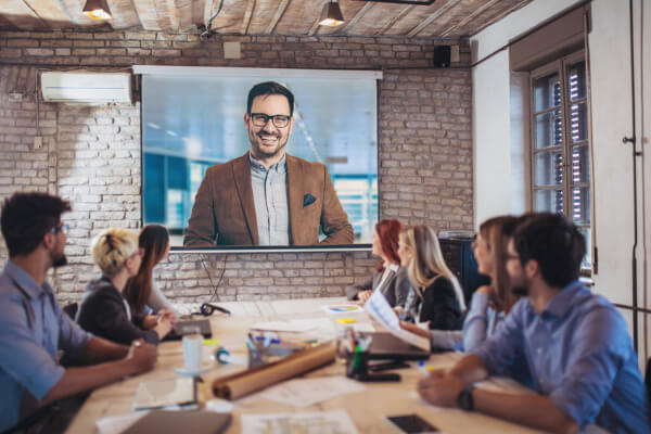 group of people sitting at a table looking at a projector