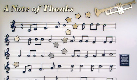 Music scale, notes, lettering, stars and trumpet laser cut from vinyl and acrylic. Individual donor names are engraved on the notes and stars.