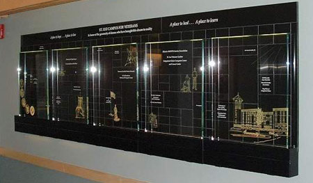 Large glass panels are set into a black Corian light box and etched with images representing all branches of military service. Black, Corian block wall is etched and color-filled with names of donors for homeless veterans.