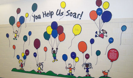 Donors are individually recognized with engraved, laser-cut acrylic balloons, with donation levels represented by varying balloon sizes.