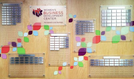 A combination of frosted acrylic panels and standoffs, decorated with silver, engraved donor nameplates and colorful laser-cut acrylic leaf figures for contrast and dimension.