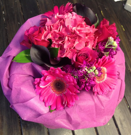 A Seasonal bouquet Wrapped in Pink with Seasonal flowers in pinks.