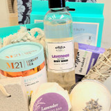 Spa gift basket featuring lavender body wash, shampoo bar, bath bomb, journal, and wellness items