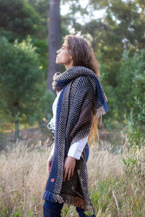 A beautifully draped shawl knitted with Wool Clasica, showcasing the luxurious warmth and rustic texture of the yarn. The hand-dyed colors blend seamlessly, creating a unique, artisanal piece that flows gracefully around the shoulders, perfect for layering over any outfit.