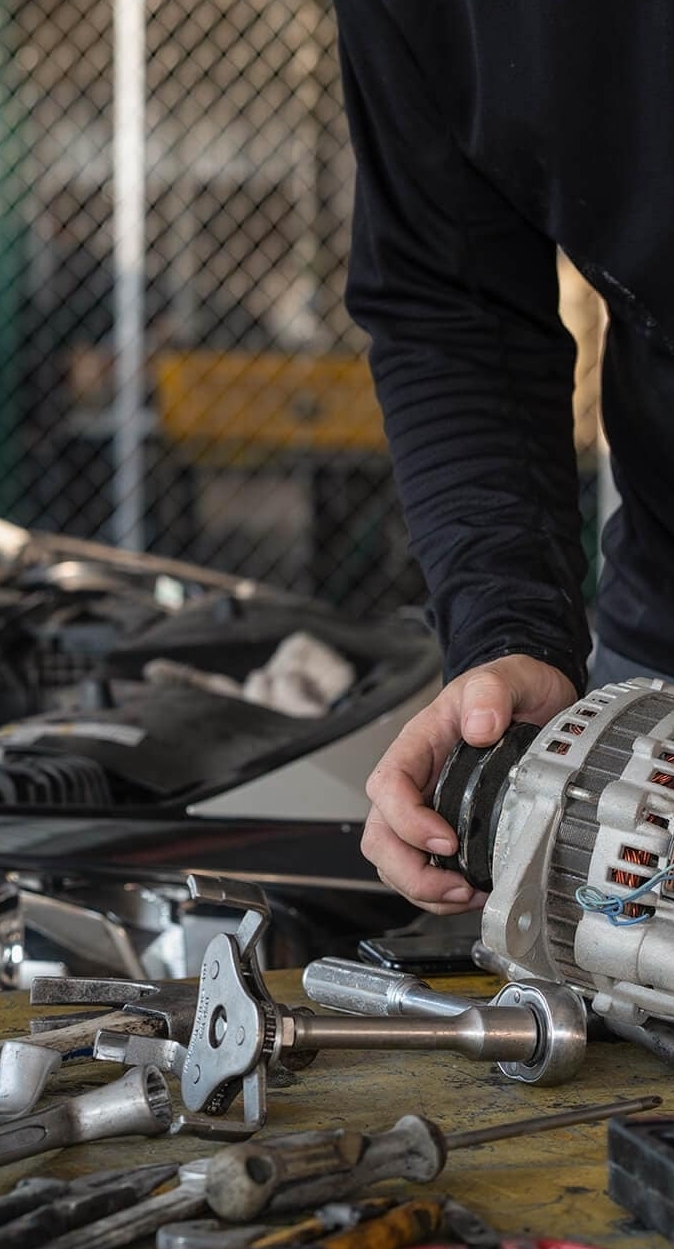 Mechanic picking up an alternator from a work bench