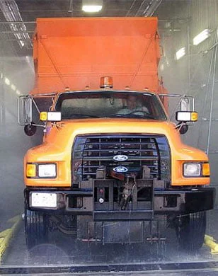 big yellow truck driving through car wash