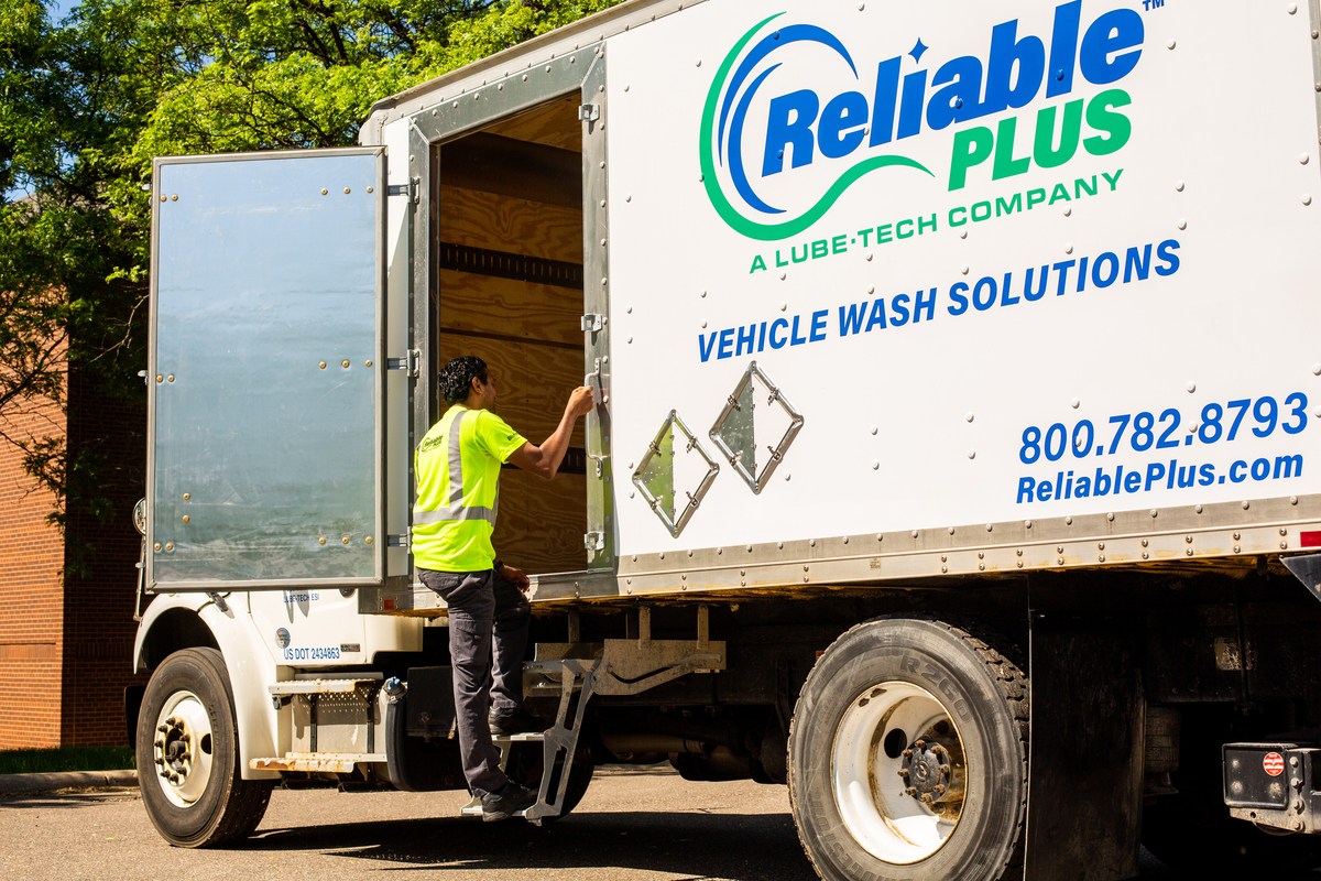 Reliable Plus employee is climbing into the back of a truck