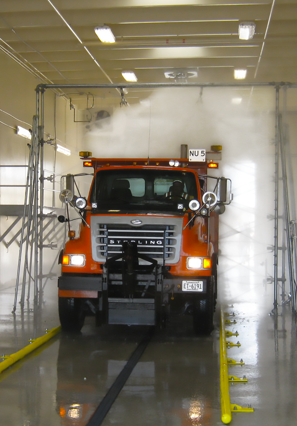 Big orange Sterling truck driving through car wash