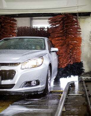 silver car driving through automatic car wash