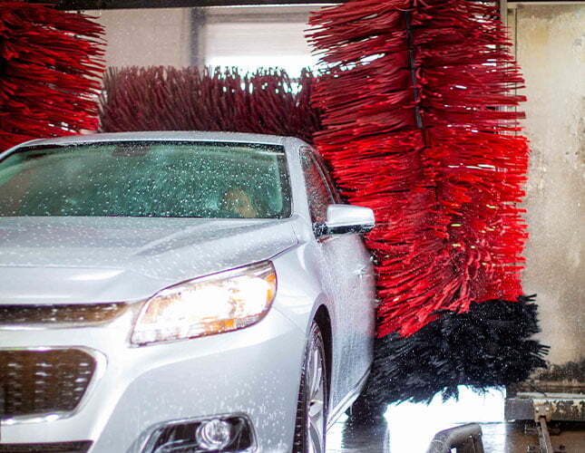 silver car driving through automatic car wash
