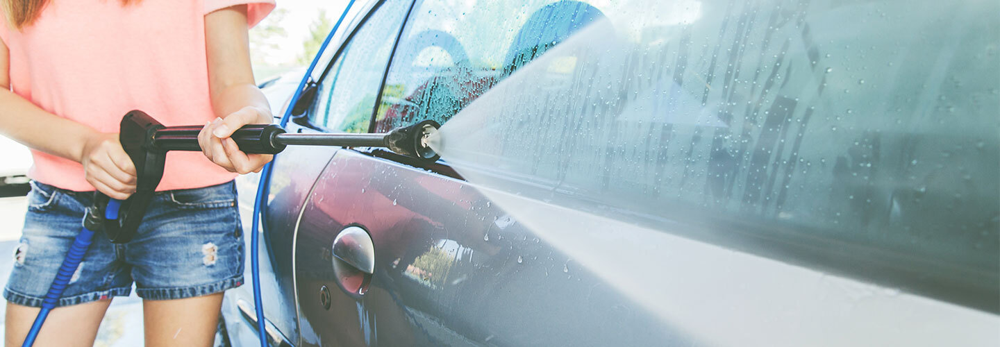Girl power washing a car