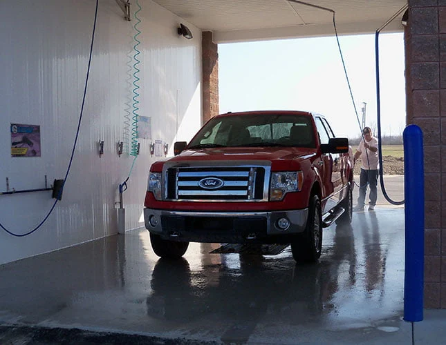Red pickup truck in self-serve wash bay