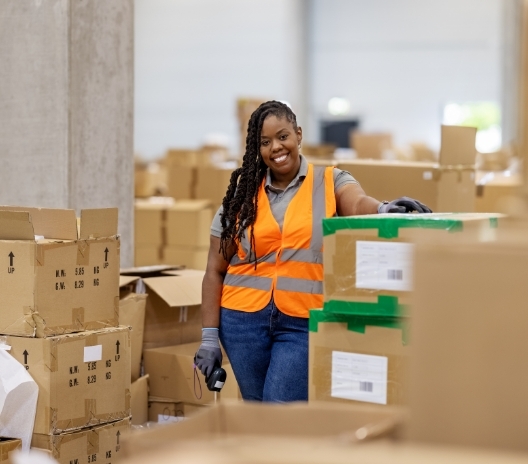 Warehouse worker scanning reused cardboard boxes as part of Genesee Scientific's sustainable shipping practices