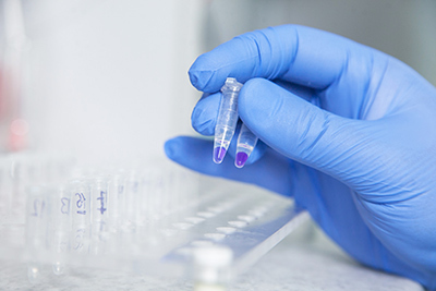 Gloved hand holding microcentrifuge tubes in a lab setting using NEXT-GEN safety gloves