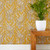 Floral stems of Muscari grow among Echinacea and meandering leaves on a mustard color wallpaper.