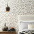 A bedroom with textural flower wallpaper in neutral tones.