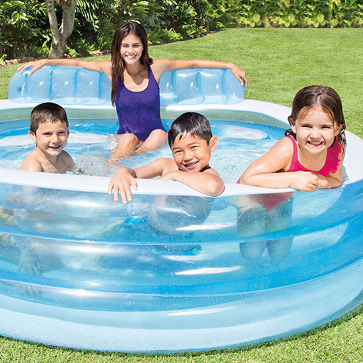 Family enjoying a blue inflatable lounge pool in the garden, featuring a built-in bench seat and padded backrest for comfortable outdoor water play.