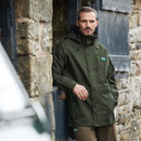 A man stood outside a barn wearing a green jacket
