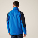 The back of a man wearing a blue and navy zipped up jacket with the hood packed away.