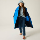 A young girl in a blue coat and denim jeans, wearing a bucket hat, walks confidently. She has long hair and is smiling slightly, conveying a relaxed mood.