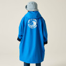 Person in blue raincoat with "Spirit of Adventure" logo, denim pants, and striped bucket hat, facing away on a plain background. Casual and adventurous vibe.