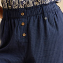 Close-up of navy striped pants featuring a gathered waistband and three wooden buttons, paired with a patterned top.