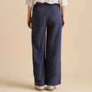 A woman wearing wide-legged, navy striped pants with an elastic waistband, viewed from the back against a neutral background.