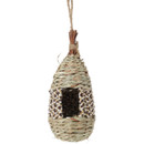 Hanging woven birdhouse made of natural fibres, featuring a teardrop shape and an open entrance, with a decorative patterned trim.