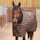 Horse standing in a stable wearing the Shires Tempest Plus Lite green tartan stable rug, featuring a breathable ripstop outer and classic tartan design.