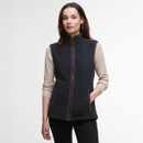 A woman in a stylish, zippered navy gilet over a beige long-sleeve top, posing against a plain white background.