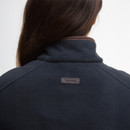 Rear view of a person wearing a dark fleece jacket with a high collar. The focus is on the jacket's texture and logo, with long brown hair visible.