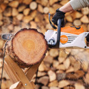 A close up of someone using the chainsaw to cut a large log