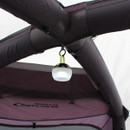 A portable lantern hangs from the ceiling of a tent, illuminating the interior with a soft glow, surrounded by dark fabrics.