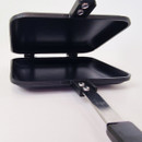 An open flat black cooking pan with a handle, showcasing its two compartments for grilling or frying.