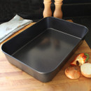 A grey metal deep roasting pan positioned on a cutting board.