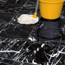 A mop rests on shiny black and white marble floor tiles beside a bright yellow cleaning bucket.