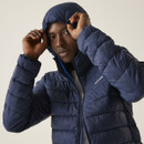 Man adjusting the hood of a navy blue puffer jacket with a calm expression. The background is light and neutral, highlighting the jacket's texture.