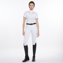 A model wears a fitted white riding outfit with a black belt and tall black boots, standing confidently against a white background.