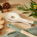 A view of a cooksmart forest fable ceramic spoon rest with an illustration of an owl with a bamboo spoon on it on a table