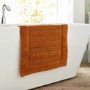 An orange bath mat draped over the bath.