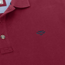 Close-up of a maroon polo shirt featuring a collared design and a dark blue embroidered logo on the chest. Close-up of a maroon polo shirt featuring a collared design and a dark blue embroidered logo on the chest.