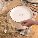 A view of a cream Woodbury Lane side plate with an etched cow design on a table
