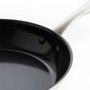 Close-up of a sleek black frying pan with a stainless steel handle, showcasing its smooth, non-stick interior and unique rivet detail.