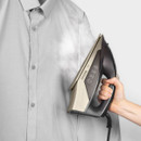 A person steaming a grey shirt with a handheld steam iron, emitting vapor to remove wrinkles.