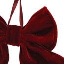 Close-up of a red velvet Christmas bow ornament featuring a plush fabric finish and hanging ribbon, ideal for elegant festive home décor.