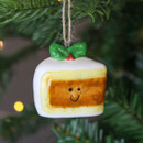 A close up view of a ceramic christmas cake hanging decoration hanging on a Christmas tree