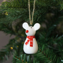 A view of a ceramic white mouse hanging decoration hanging on a Christmas tree