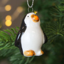 A close up view of a ceramic  penguin hanging decoration hanging on a Christmas tree