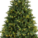 A close-up of a lush, green artificial Christmas tree adorned with warm yellow lights, ready for holiday decoration.