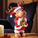 A cute plush reindeer wearing a Santa suit plays a saxophone, sitting on a table beside a candle and festive decorations.